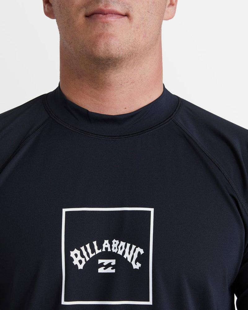 Close-up of Billabong logo on black rash vest featuring arched text and wave graphic in white.