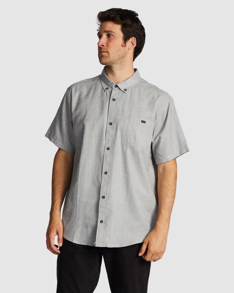 Grey short sleeve button-up shirt with black pants, front view.