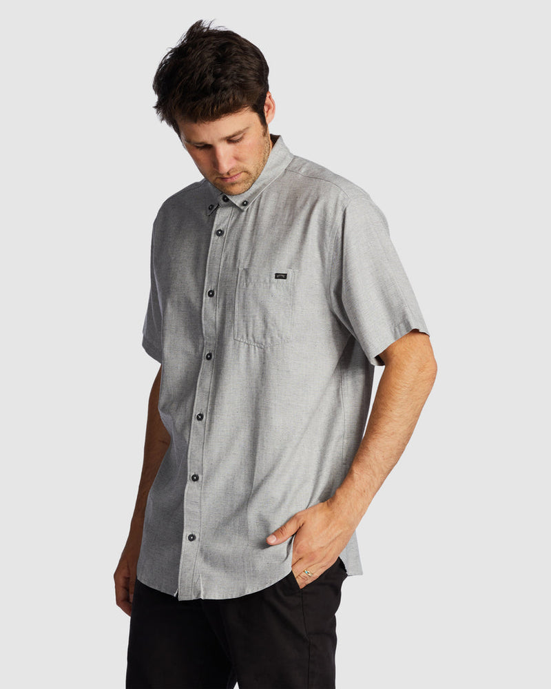 Rear angle of grey short sleeve shirt with curved hem and relaxed fit.