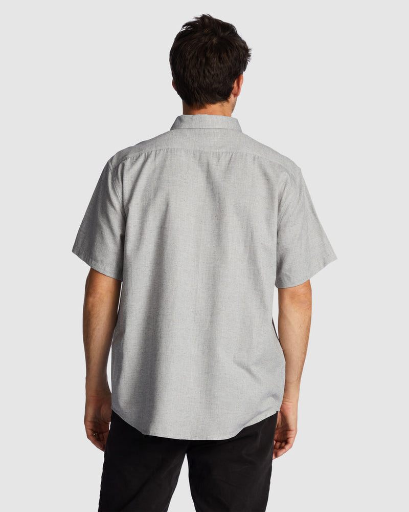 Back view of grey button-up shirt and black pants.