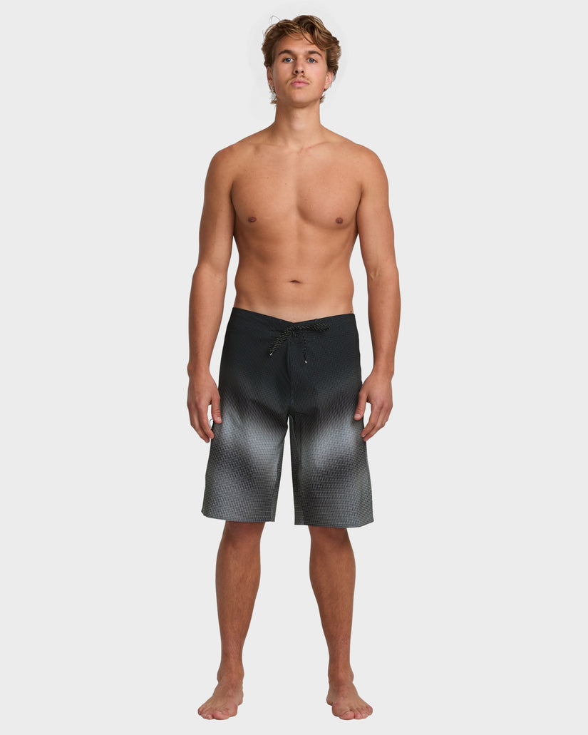Full-length front view of model wearing black gradient boardshorts with drawcord waist.