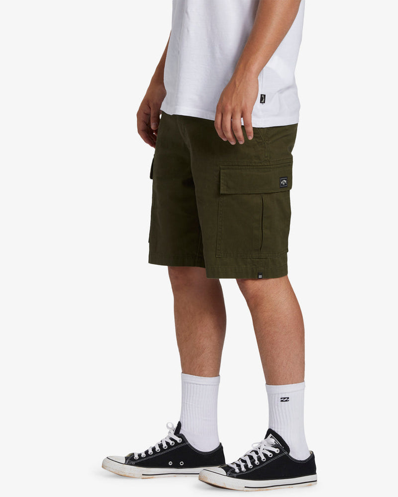 Side view of men's olive green cargo shorts with flap pockets, styled with black Converse and white crew socks.