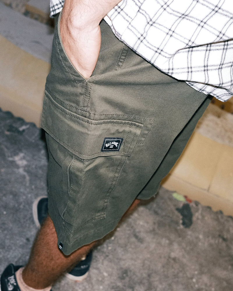 Angled side view of olive green cargo shorts showing pocket detail and relaxed fit above the knee.