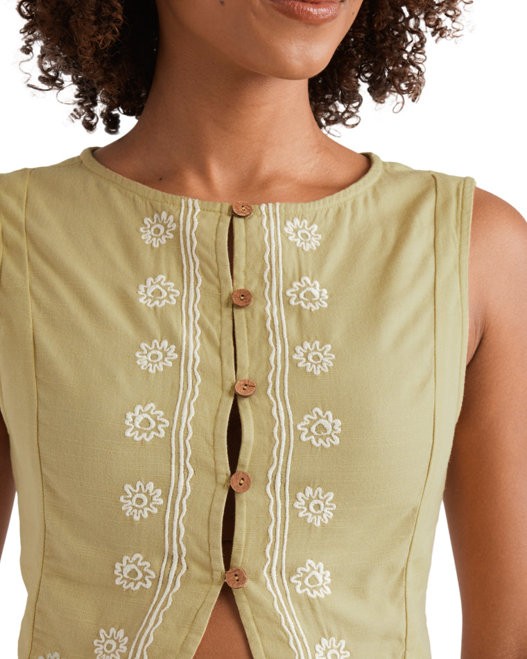 Close-up of yellow crop top with wooden buttons and white floral embroidery.