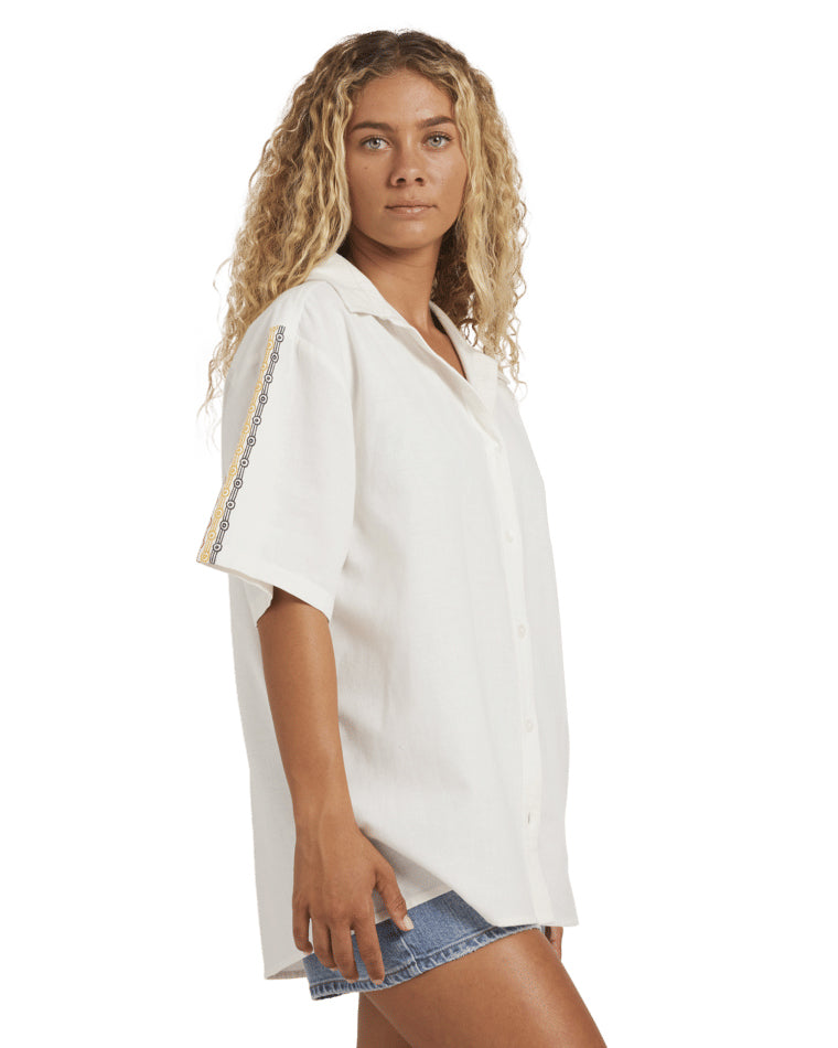 Relaxed white button-up shirt with short sleeves, yellow and blue embroidery detail on sleeve.