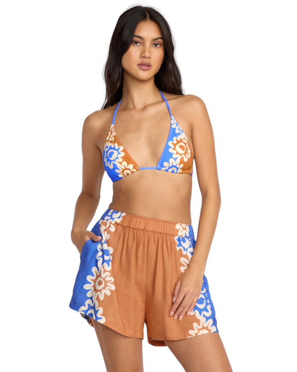 Women's triangle bikini top and relaxed floral shorts in bright blue, tan and cream.