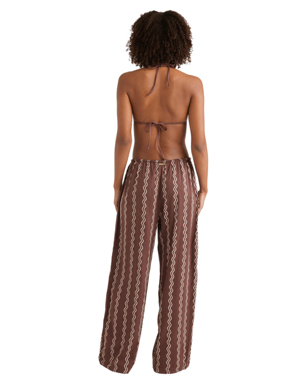 Back view of woman in brown printed pants and brown bikini top, showing tie-back detail and relaxed fit.