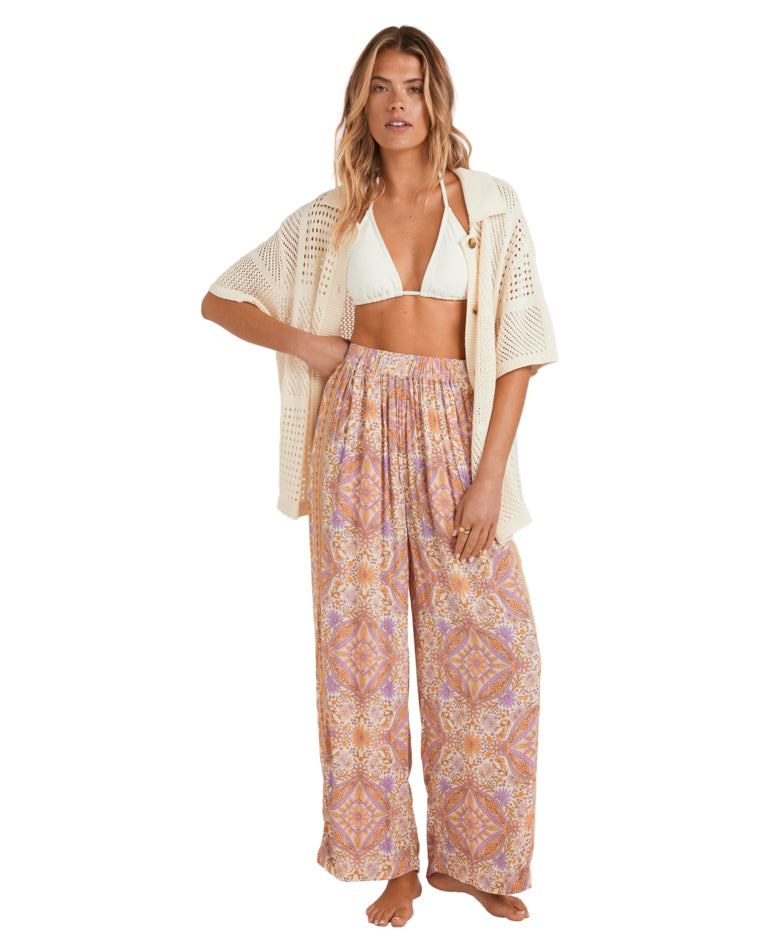 Cream knit short-sleeve shirt worn open over a white bikini top and wide-leg printed pants