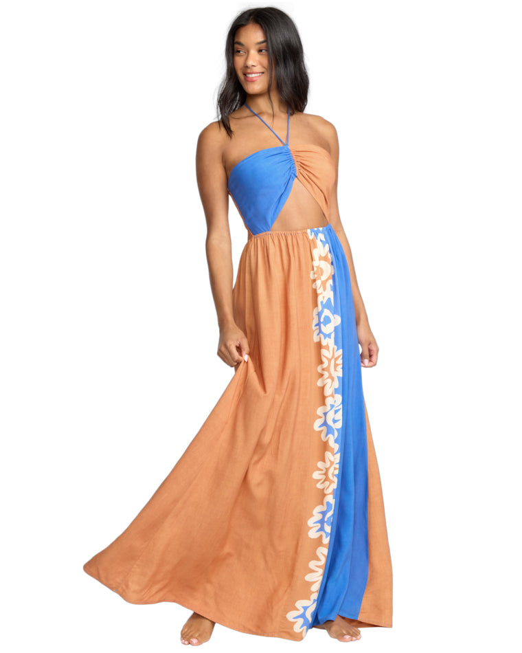 Side view of a halterneck maxi dress with asymmetric blue and tan panels and floral print along the seam.