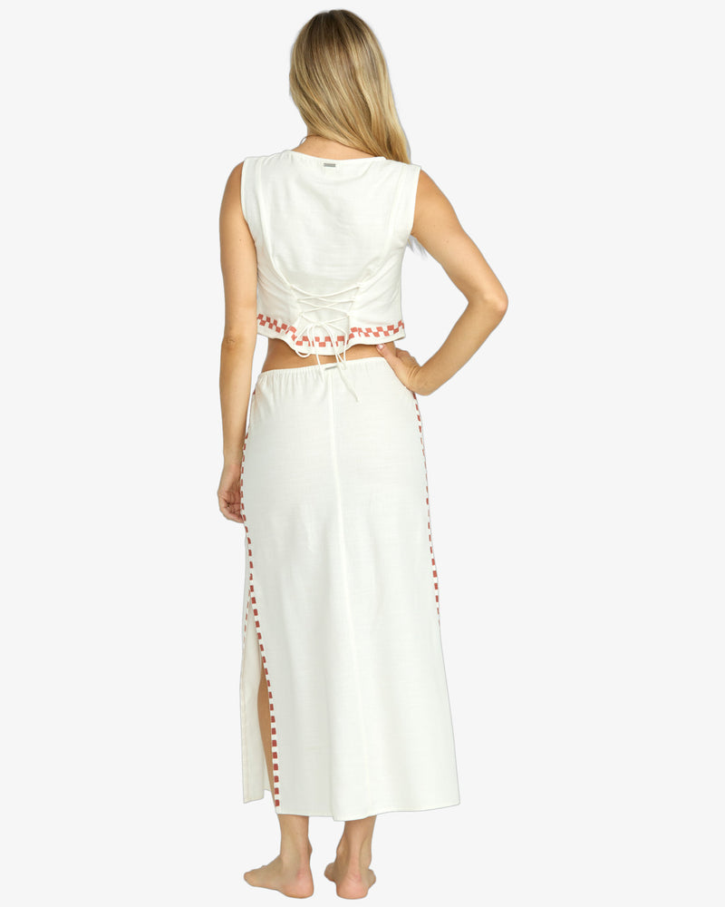 Back view of cream crop top with lace-up tie and matching maxi skirt with red trim.