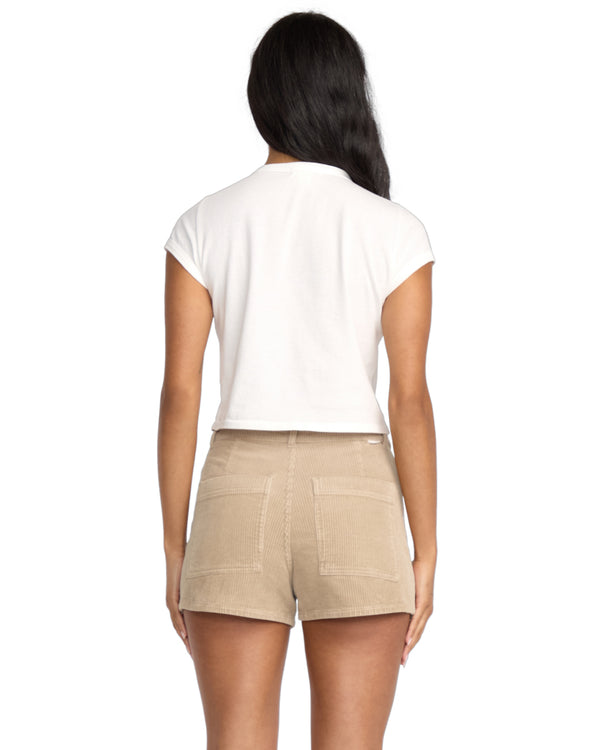 Back view of model wearing beige corduroy shorts with patch pockets and a white cropped tee.