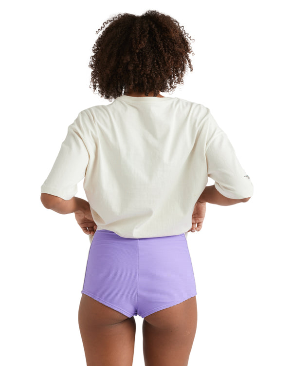 Back view of woman wearing oversized tee and purple ribbed shorts.