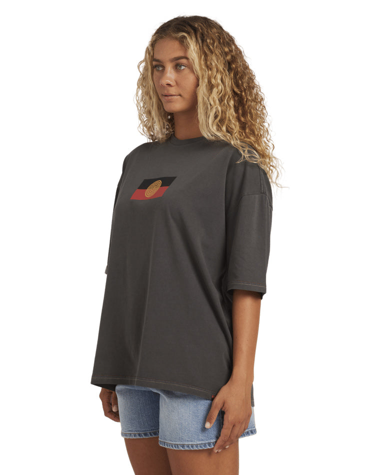 Side view of the black Billabong tee showing the fit and relaxed sleeve, worn with light blue denim shorts.