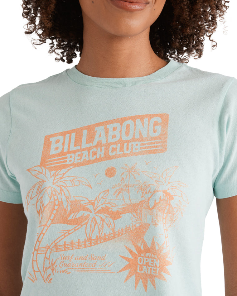 Close-up of orange “Billabong Beach Club” graphic with palm trees and “Open Late” text on light blue tee.