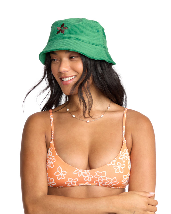 Green bucket hat with floral embroidery worn by a woman smiling and looking sideways.