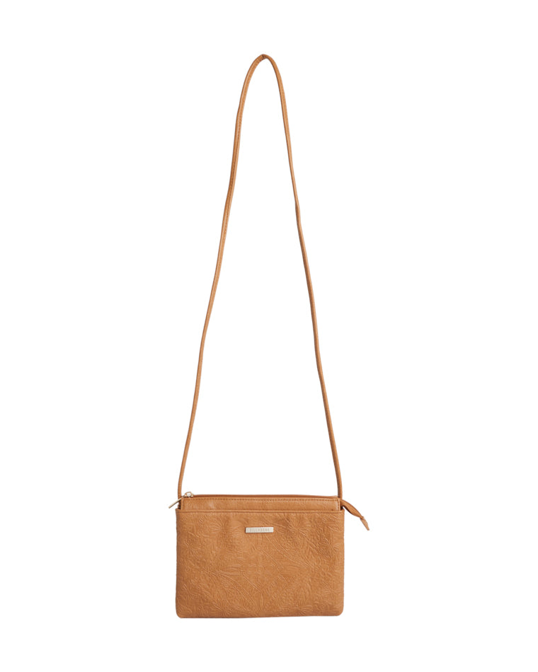 Front view of tan Billabong crossbody bag with floral embossing and metal logo plate.