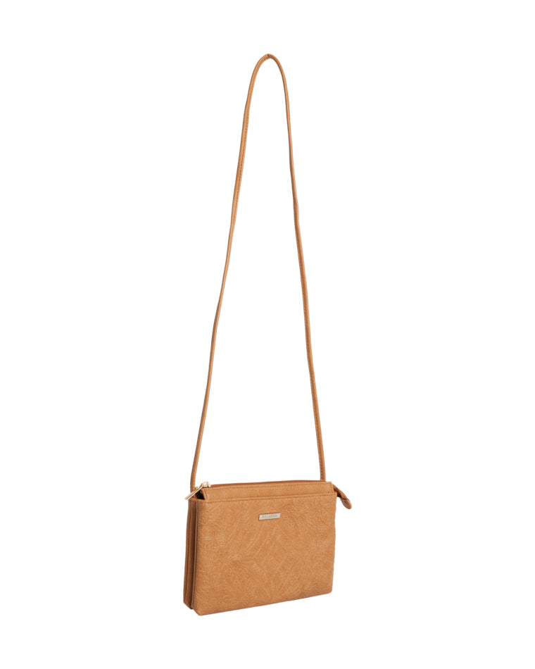 Angled side view of tan Billabong bag showing slim profile and floral embossed detailing.