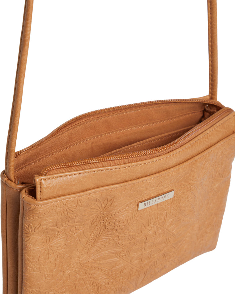 Close-up of inside tan Billabong bag revealing zip compartments and embossed exterior.