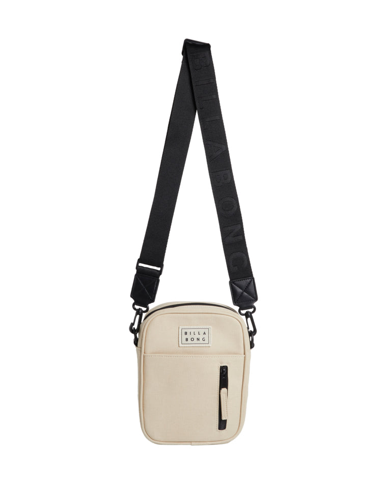 Beige Billabong crossbody bag with a front pocket and black zip, featuring a wide black branded strap.