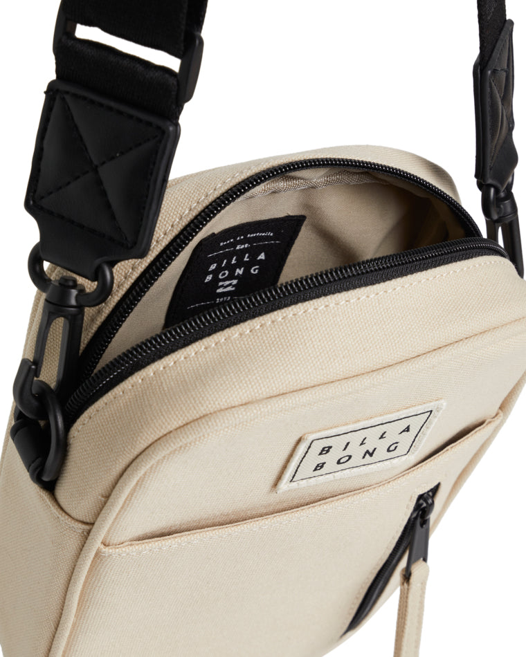 Close-up of the beige Billabong crossbody bag showing inside lining and Billabong label near zip opening.