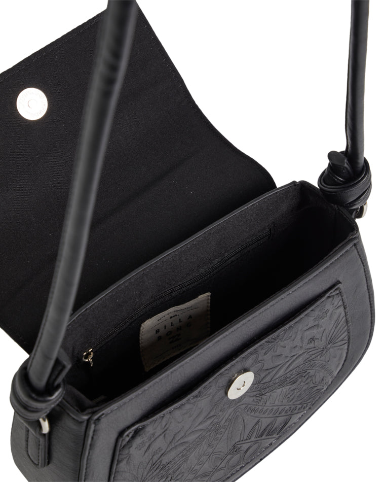 Interior of black crossbody bag with magnetic flap open, showing zip pocket and fabric lining.
