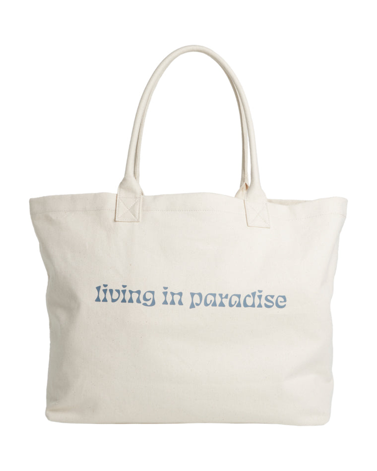 Back view of cream canvas tote bag with light blue text reading "living in paradise".