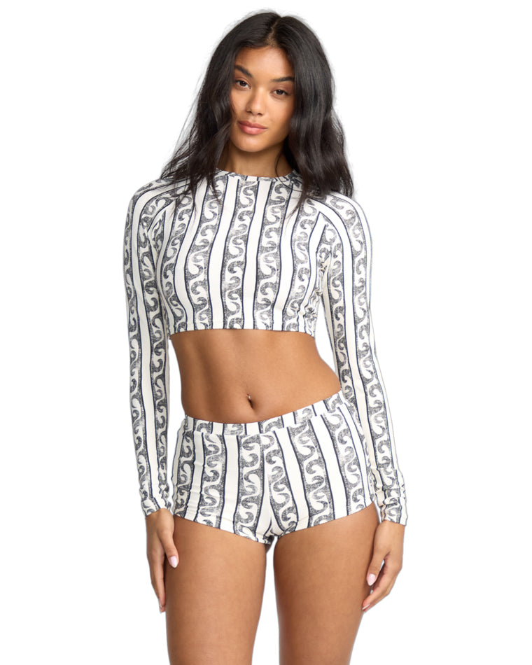 Model wears a long sleeve crop top with black and white vertical swirl stripe print, paired with matching high-waisted shorts.