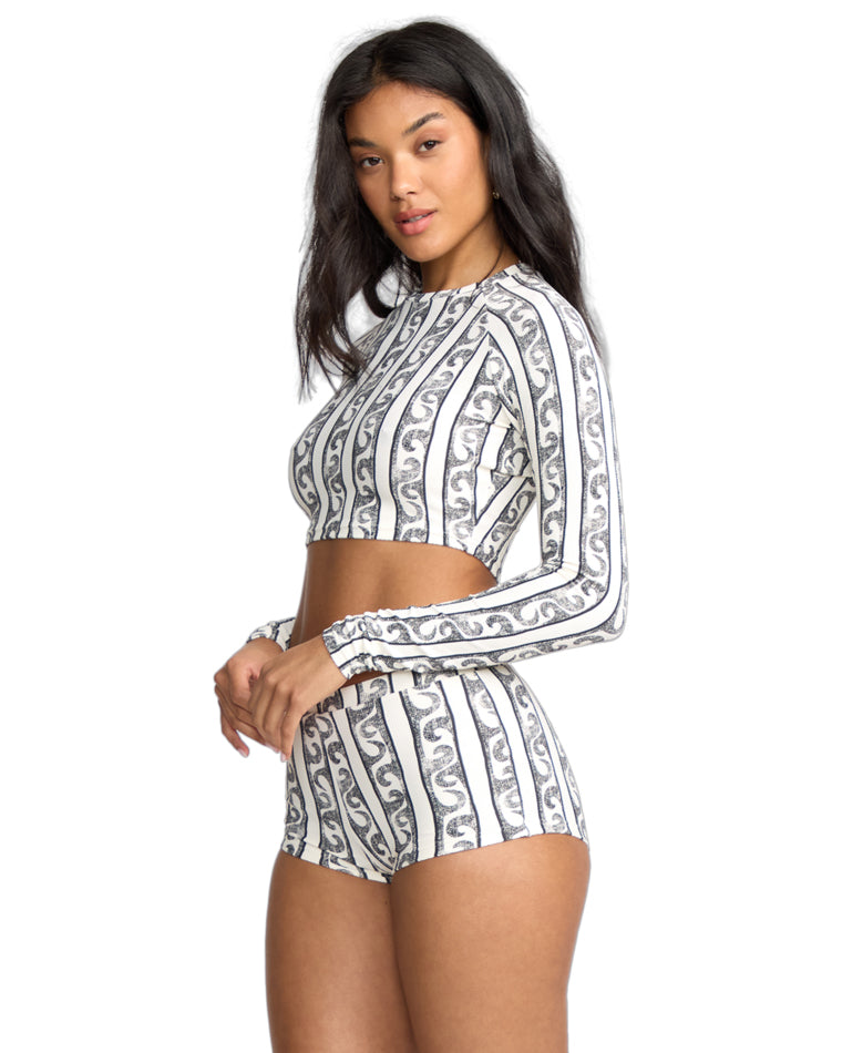 Side view of model in matching black and white swirl stripe crop top and shorts with a bodycon fit.