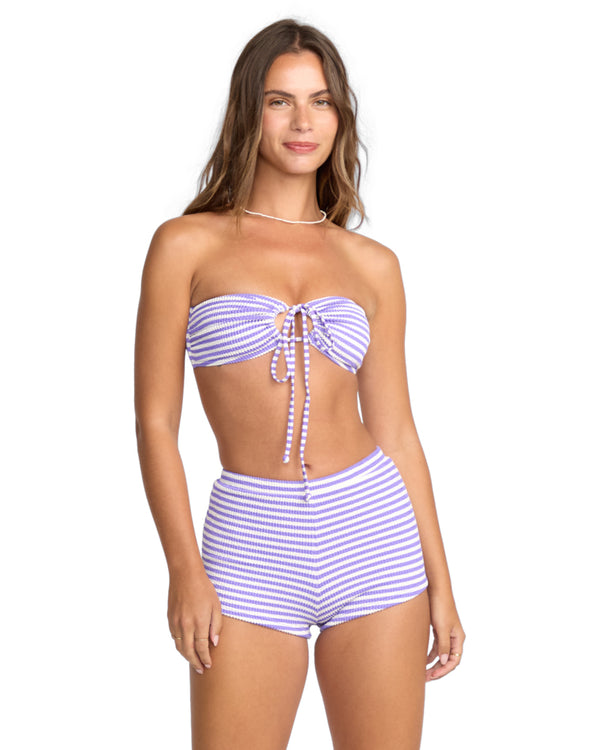 Woman wearing a purple and white striped bandeau bikini top with high-waisted matching shorts.