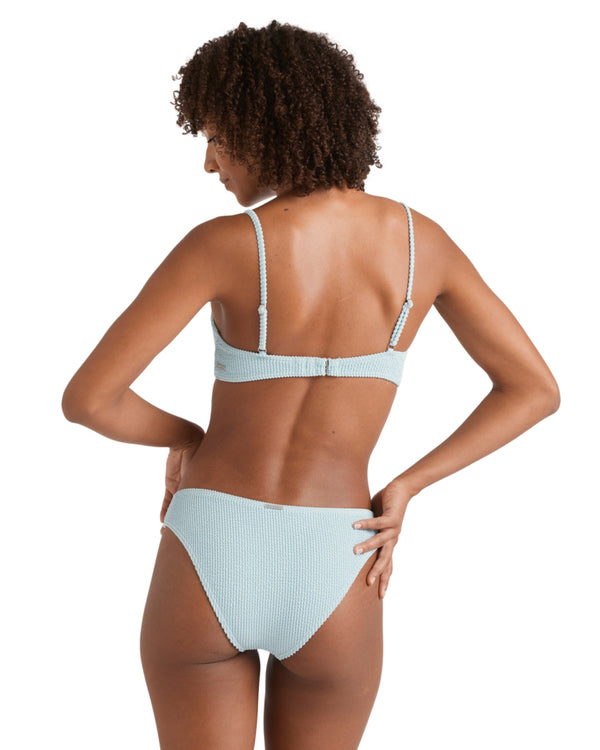 Back view of a woman wearing a textured light blue bikini top with hook closure and adjustable straps.