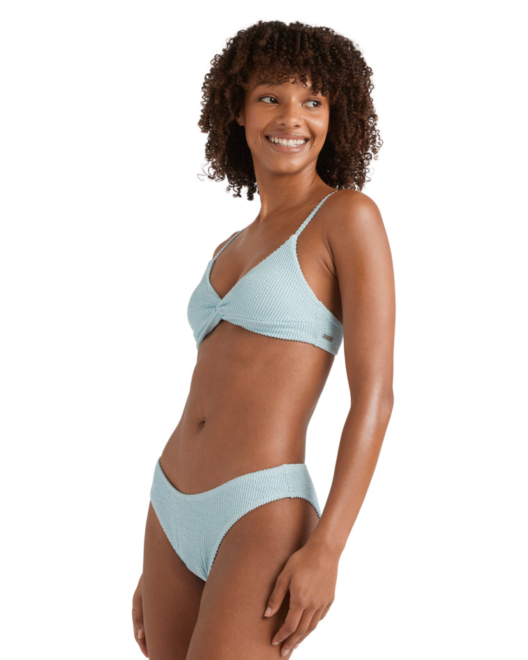 Side angle of a woman smiling in a textured light blue bikini top with subtle ribbed detail.