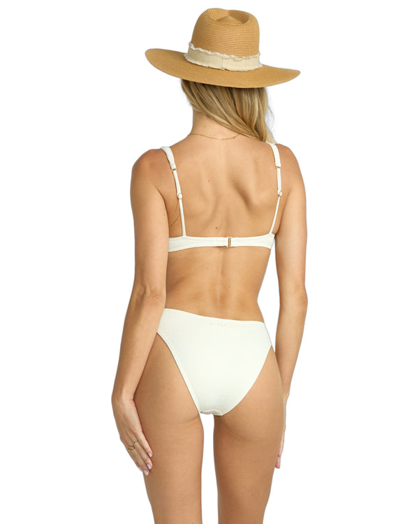 Back view of woman wearing a white textured bikini with adjustable straps and clasp closure, paired with a straw hat.