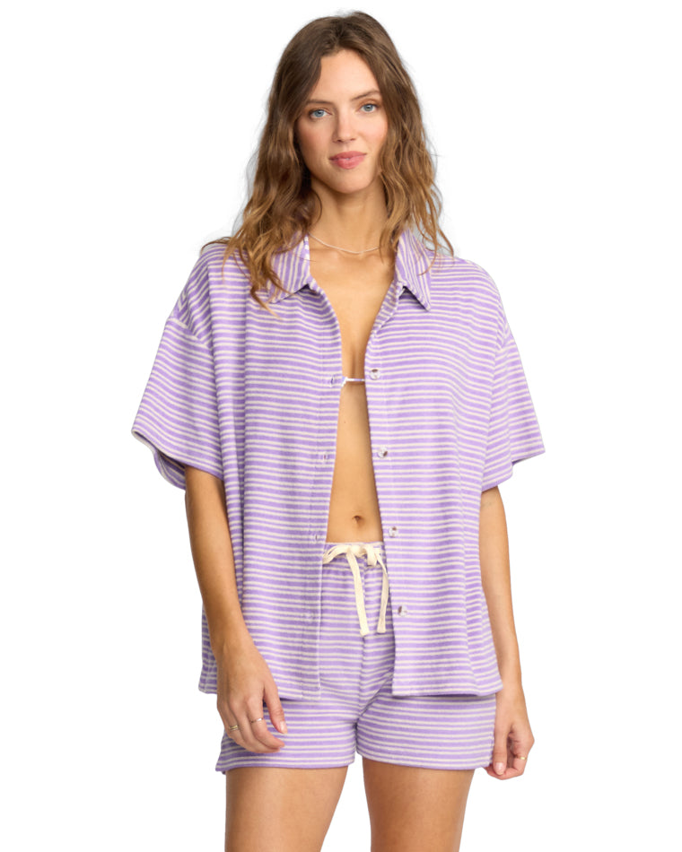 Woman wearing a short-sleeve lavender and white striped button-up shirt with matching drawstring shorts.
