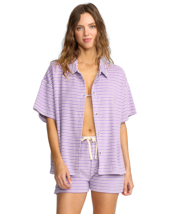 Woman wearing a short-sleeve lavender and white striped button-up shirt with matching drawstring shorts.