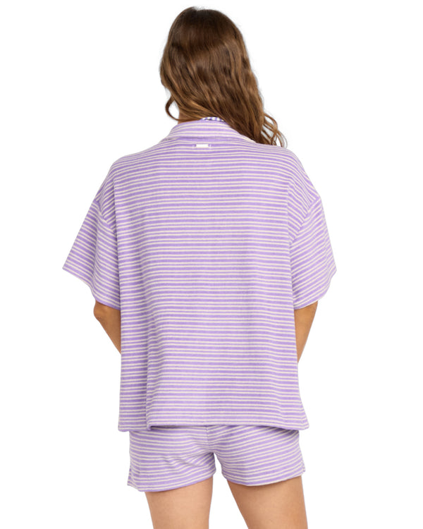 Back view of woman in a lavender and white striped shirt and shorts set.