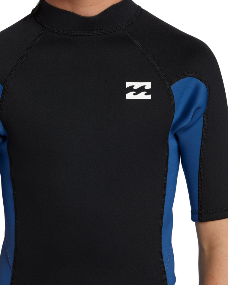 Close-up of chest showing the white Billabong logo on black wetsuit with blue sleeve detail.