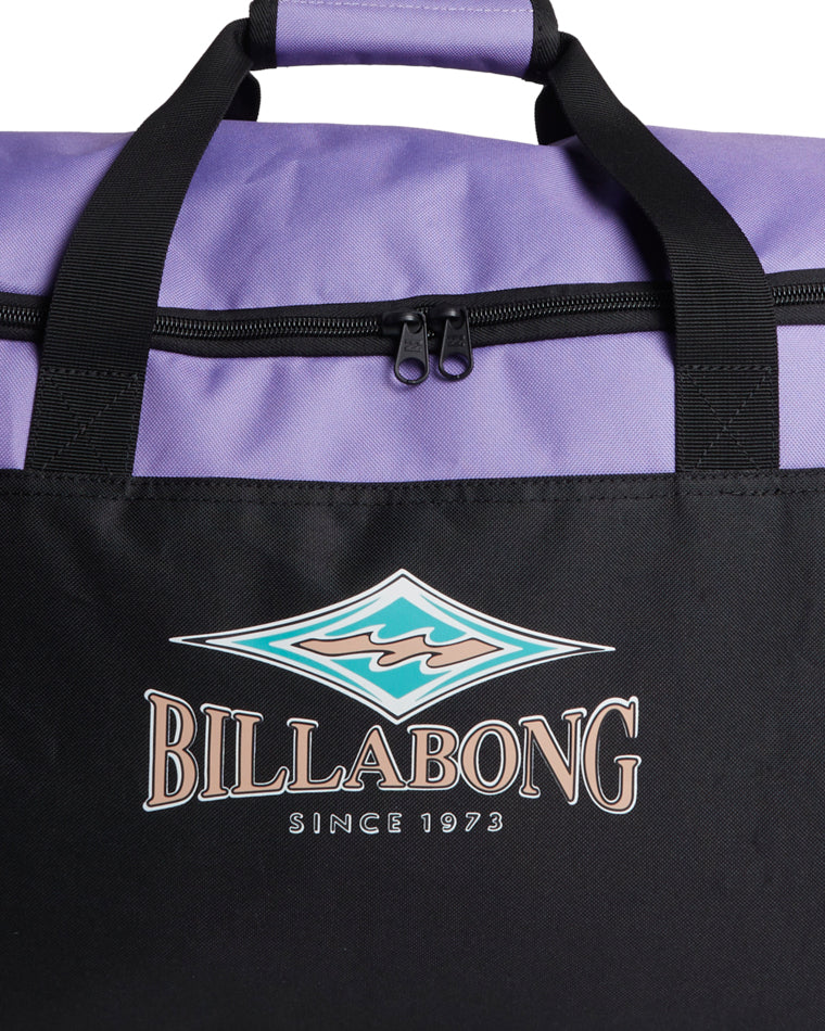 Close-up of Billabong logo and zipper on purple and black duffle bag.