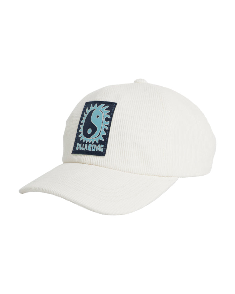 Side angled view of cream corduroy cap with curved brim and navy Billabong sun yin-yang patch on the front.