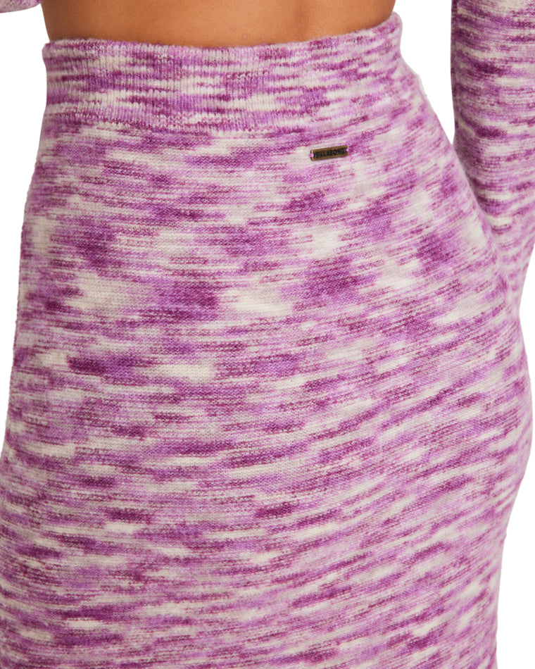 Close-up of a marled pink and white knit maxi skirt with a high waist, featuring a small metallic brand logo detail.