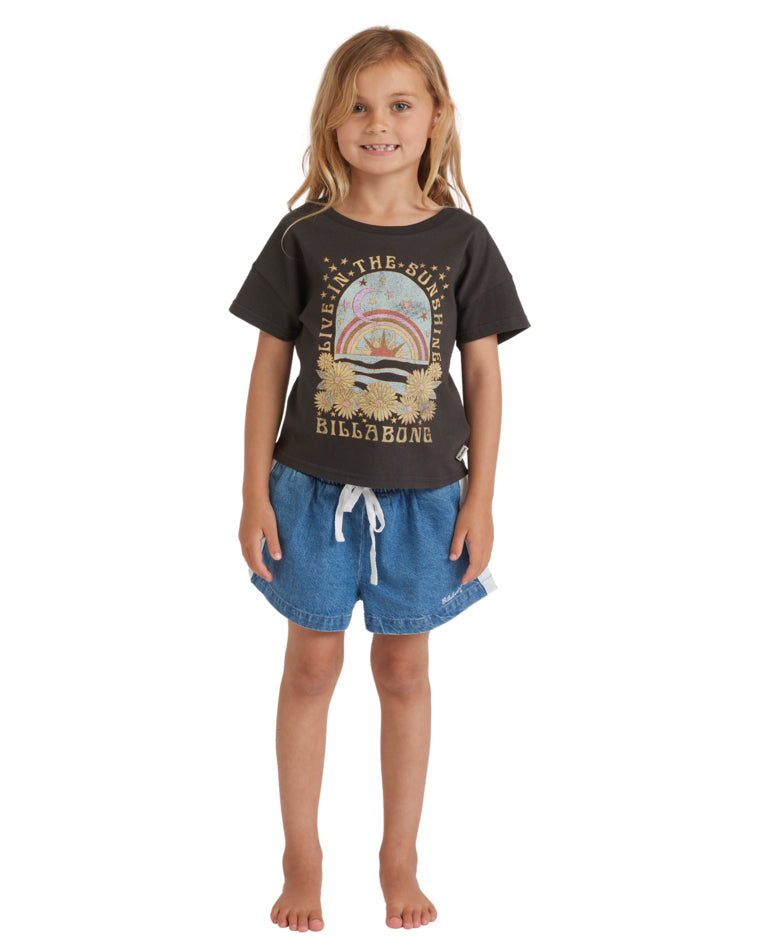 Girl wearing a black graphic t-shirt with “Live in the Sunshine” text, paired with drawstring denim shorts, standing front-facing.