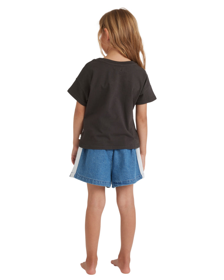 Back view of a girl wearing a black graphic tee and denim shorts with contrast side panels.