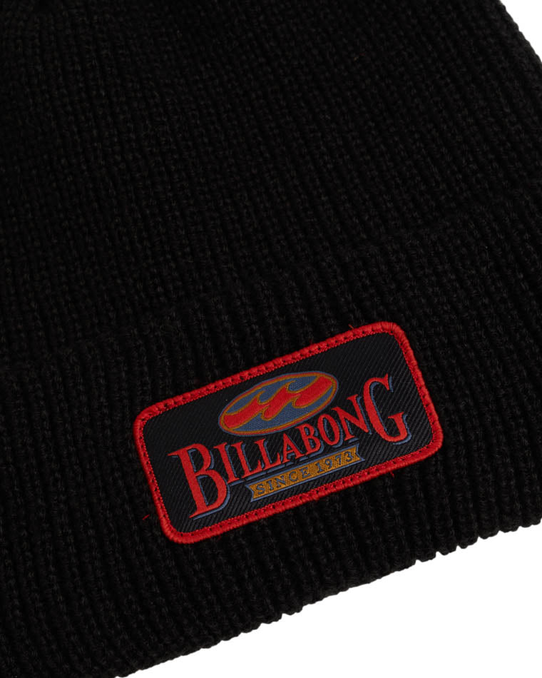 Close-up of a black knit beanie featuring a Billabong patch with red and gold embroidery, outlined in red stitching.
