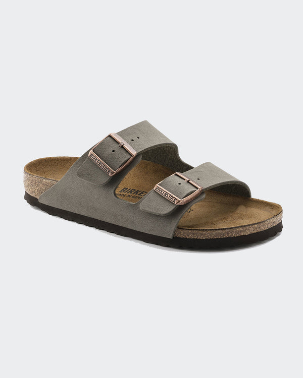 Birkenstock slides featuring two adjustable suede straps with metallic buckles, cork footbed, and a comfortable sole.