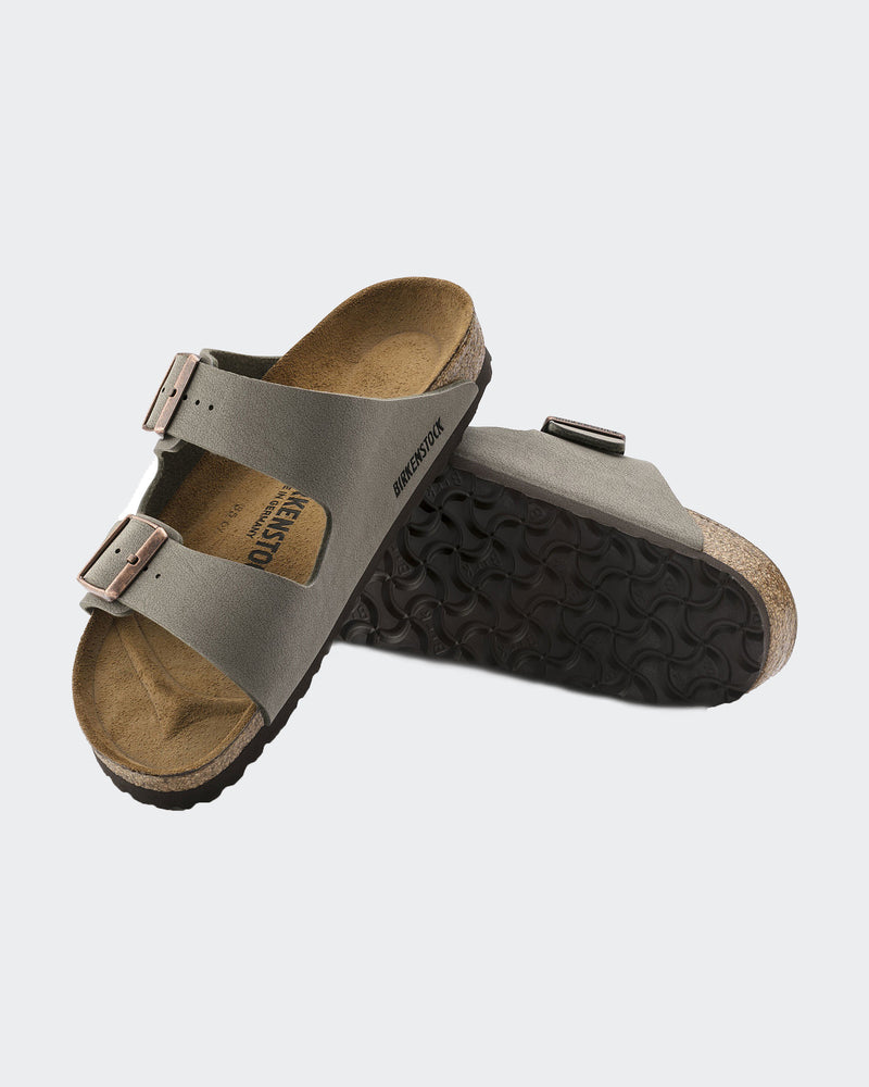 Birkenstock slides showing gray suede straps with metallic buckles, a cork footbed, and a durable textured sole design.