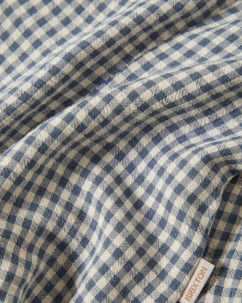 Close-up of blue and white gingham fabric with a soft texture, showcasing fine weave details and a small branded tag.