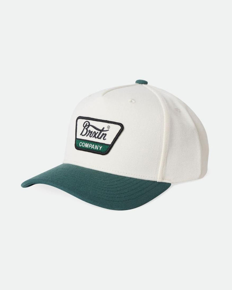 White snapback cap with a forest green brim and embroidered "Brixton Company" patch on the front.