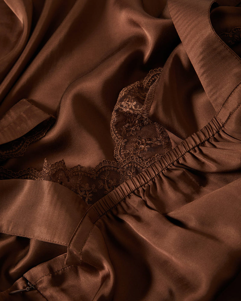 Close-up of brown satin slip dress with delicate lace trim, showcasing its luxurious texture and intricate detailing.