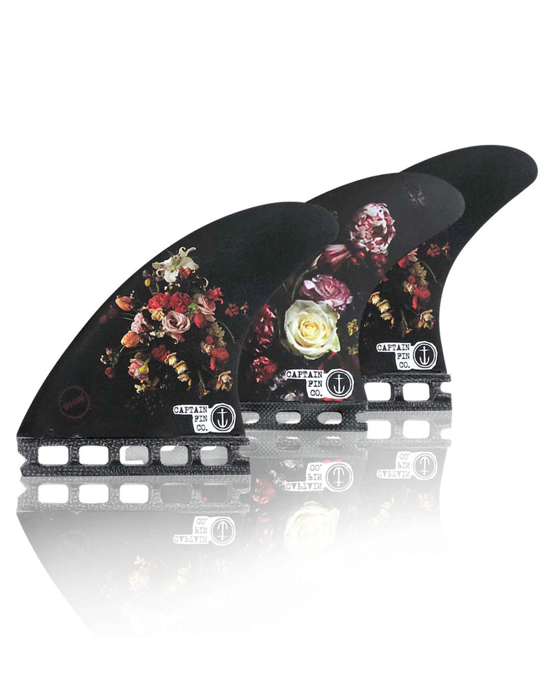 Set of three Captain Fin Co floral surfboard fins with mixed bouquet designs and dual tab bases.