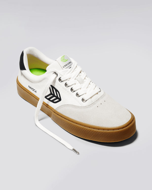 White Cariuma Naioca skate shoe with black logo, gum sole, green insole, and untied laces, displayed on a light background.