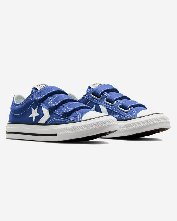 Pair of blue Converse sneakers with white star and chevron logo, velcro straps, and rubber toe caps on a white sole.